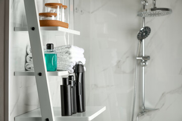 Stack of towels, shampoo and other toiletries on shelves near shower stall in bathroom, space for...