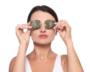 Beautiful woman applying green tea bags on skin under eyes against white background