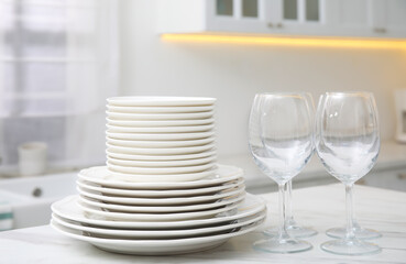 Set of clean dishes and glasses on table in stylish kitchen
