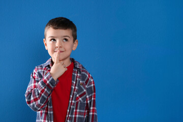Thoughtful little boy on blue background, space for text - obrazy, fototapety, plakaty