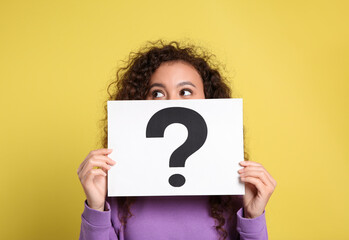 African-American woman with question mark sign on yellow background