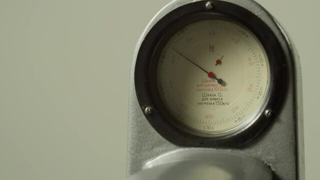 Moving instrument pointer on face of loading meter with different scales on light background closeup. Materials processing checkup
