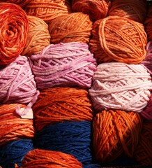 Empilement de pelotes de laine dans les tons orange et rose