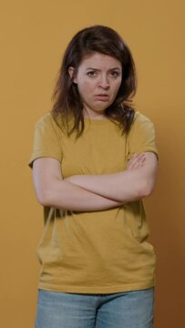 Seriously upset woman with arms crossed feeling sad and disappointed looking grumpy mumbling in studio. Bored young person feeling annoyed and stressed because of personal problems.