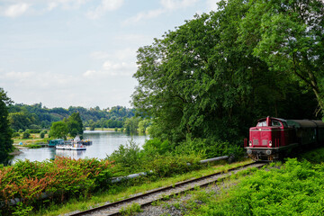 Red train on the Ruhr with surrounding landscape. Railway line in North Rhine-Westphalia.
