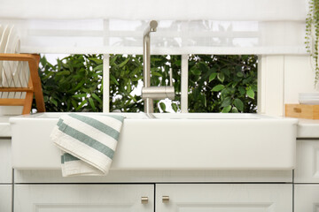 Clean towel hanging on white sink in kitchen