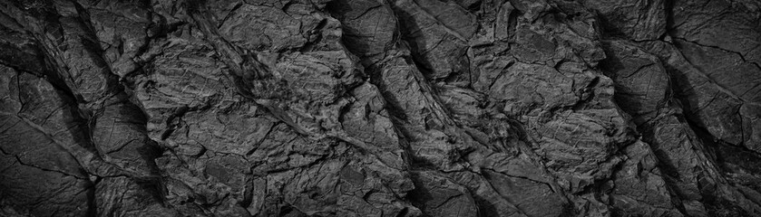 Black white rock texture background. Rough mountain surface with cracks. Close-up. Dark gray stone...