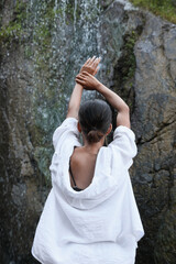 Young woman near beautiful waterfall outdoors, back view