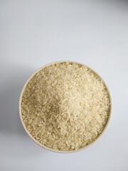 White raw rice in a bowl, on a white background top view