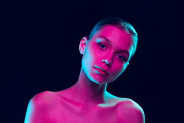 Portrait of tender young woman posing isolated over dark background in neon light. Concept of...