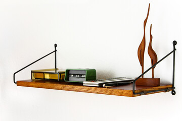 midcentury teak shelf on white wall in the living room with a wooden vase and a plack pen on it...