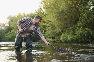 Fisherman picking up big rainbow trout from his fishing net