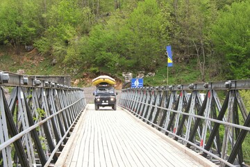 View of SUV arriving with a rafting boat crossing wooden board  from the Bosnian bored to Montenegro