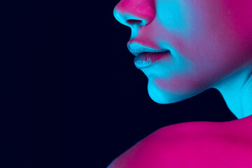Obraz premium Closeup female lips, cheeks and nose isolated over dark background in neon light. Concept of cosmetology, skincare, cosmetics, plastic surgery, ad