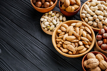 set of different nuts on a black rustic wooden background