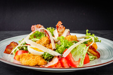 salad with fried chicken and bacon on a black background