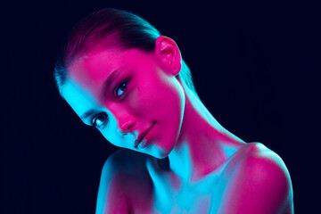 Portrait of tender young woman posing isolated over dark background in neon light. Concept of...