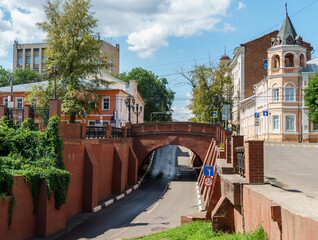 Picturesque red stone bridge overhangs across the road. Bridge was  designed by Voronezh architect...