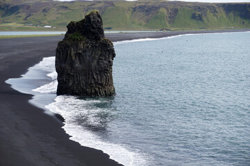Reynisfjara - black beach in Iceland, single rock and cliffs