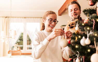 Happy caucasian family decorating Christmas tree. Country home - living room interior.