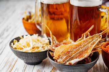 mug of beer and a set of dry fish snacks on a white wooden rustic background