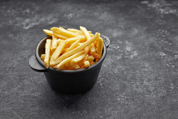 French fries in cast iron on gray concrete
