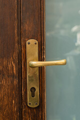 Metal brass old gold colored doorknob on a wooden brown door in Italy