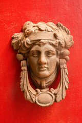 Vintage metal doorknob, knocker (gong) on a red door