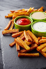 golden french fries on a black rustic wooden background