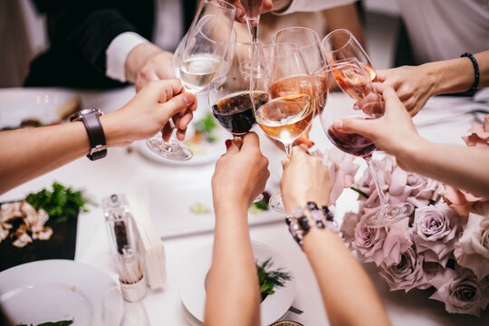 Cheers! Group Of People Cheering With Champagne Flutes With Home Interior In The Background. Restaurant Chilling Out Classy Lifestyle Reserved Concept. Friends Clinking Glasses Above Dinner Table. 