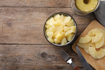 Flat lay composition with canned pineapple on wooden table. Space for text