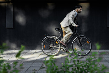 Businessman riding bicycle in front of modern office building.