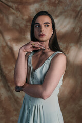 Naklejka premium Brunette queer person in sundress looking away on abstract background.