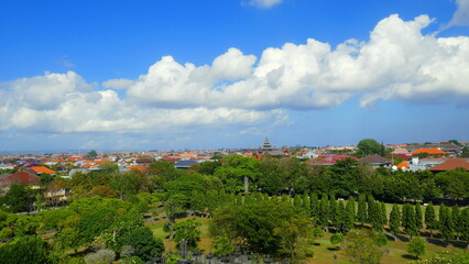 Fototapeta na wymiar Blick vom Nationaldenkmal in Bali zur Befreiung von Holland auf den Park und Hauptstadt Denpasar bei blauem Himmel und weißen Wolken