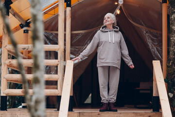 Woman relaxing at glamping camping tent. Modern vacation lifestyle concept