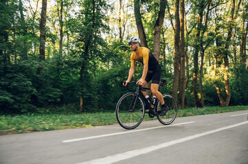 Naklejka premium Athletic man in sport clothes riding a bike in the nature
