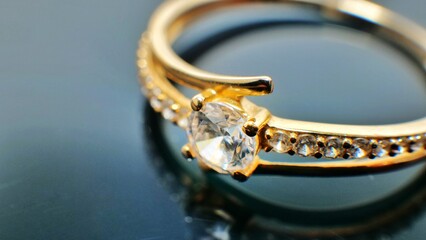 Gold jewelry ring with diamond on reflected black table