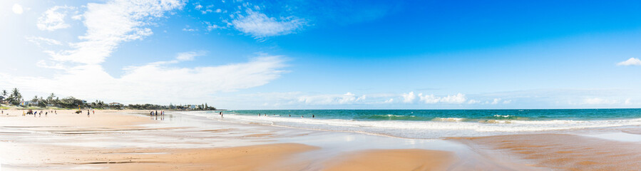 Fototapeta na wymiar Panorama of sandy beach and ocean waves on a sunny day. Nature tropical background. Low tide. Kellys Beach, QLD, Australia