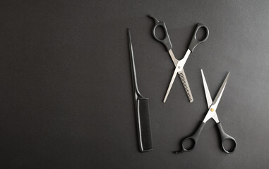 Hairdressing background with two scissors and comb on black background