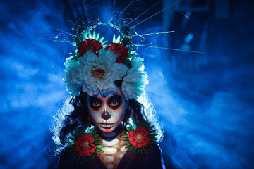 Woman with mexican skull halloween makeup on dark background. Day of the dead aka Dia de los Muertos and halloween traditional celebration.