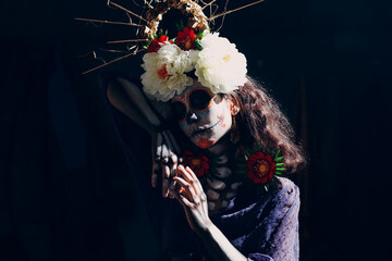 Woman with mexican skull halloween makeup on dark background. Day of the dead aka Dia de los...