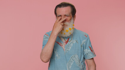 I am watching you. Senior man with flowers in gray-haired beard pointing at his eyes and camera,...