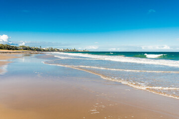 Beautiful ocean sandy beach nature background with town on the horizon. Low tide.