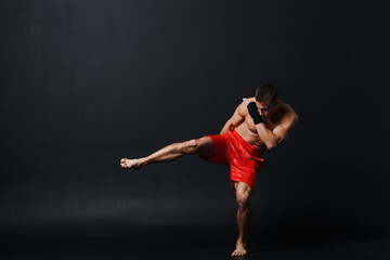 Sportsman muay thai man boxer stance at black background.