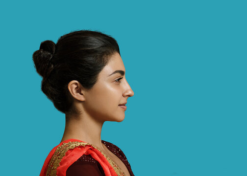 Young indian woman beauty profile portrait in sari on blue background.
