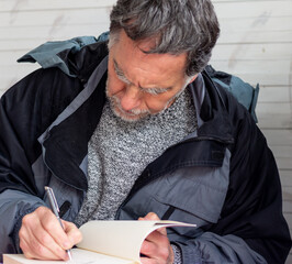 man with beard and gray hair writes a book