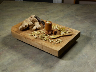 Dried and fresh ginger with a mortar and pestle on a wooden cutting board