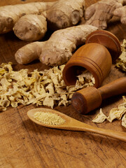 Dried and fresh ginger with a mortar and pestle on a wooden cutting board
