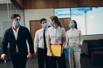 Businessman and businesswoman team in face masks walking along the wall to office meeting. Business people group conference discussion concept