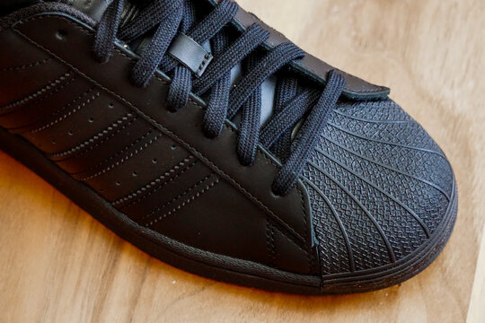 10 July 2022 Eskisehir Turkey.Brand new black adidas superstar shoes on wooden background